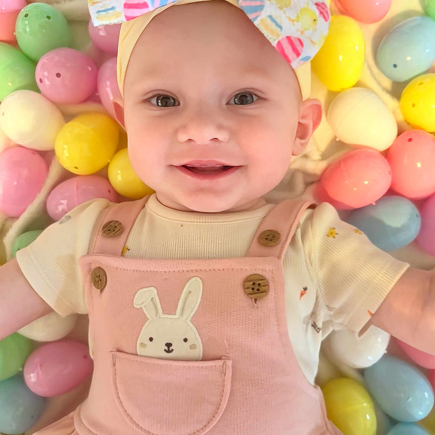 Sophia joined the competition — help win amazing prizes! baby, baby_clothing, bow, bunny_patch, child, cute, easter_eggs, face, happy, headband, holiday_theme, indoor, infant, lying_down, pastel_colors, pink_outfit, playful, portrait, smiling, soft_lighting