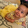 baby, child, yellow_dress, tutu, smile, face, eyes, carpet, pattern, indoor, cute, curly_hair, sneakers, floor, infant, playful, person, toddler, happy, clothing