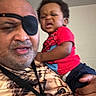 Kobe joined the competition — help win amazing prizes! baby, child, adult, man, selfie, portrait, holding, family, indoor, face, eyepatch, camouflage, red_shirt, blue_pants, sitting, closeup, expression, funny, home, photography