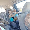 Sebastian is registered to the contest to win money with this photo: child, toddler, car, car_seat, teddy_bear, stuffed_animal, hugging, sitting, portrait, indoors, vehicle_interior, passenger, seatbelt, blue_shirt, toy, brown_bear, rear_seat, family_car, daylight, photograph