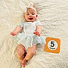 baby, infant, smiling, headband, bow, milestone_card, five_months, blue_dress, lying_down, blanket, textured_blanket, cute, happy, child, human, portrait, indoor, infant_fashion, baby_photography, celebration