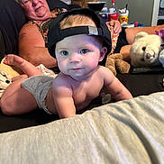 Jessica is registered to the contest to win money with this photo: adult, baby, backwards_cap, bed, blanket, child, couch, diaper, eyes, face, home, indoors, infant, living_room, lying_down, portrait, sitting, stuffed_animal, teddy_bear, woman