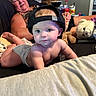 adult, baby, backwards_cap, bed, blanket, child, couch, diaper, eyes, face, home, indoors, infant, living_room, lying_down, portrait, sitting, stuffed_animal, teddy_bear, woman