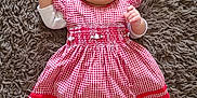 Nirina a rejoint le concours — aidez-le/la à gagner de superbes lots ! adorable, baby, carpet, cheerful, child, comfortable, cute, fluffy_rug, headband, indoors, infant, lying_down, patterned_clothing, person, portrait, red_dress, small_hands, smiling, soft_texture, young_child