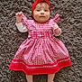 adorable, baby, carpet, cheerful, child, comfortable, cute, fluffy_rug, headband, indoors, infant, lying_down, patterned_clothing, person, portrait, red_dress, small_hands, smiling, soft_texture, young_child