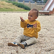 Kayden a rejoint le concours — aidez-le/la à gagner de superbes lots ! casual_clothing, child, curious, daylight, exploration, expression, fun, happy, nature, outdoor, pebbles, playground, playing, shoes, sitting, slide, smiling, toddler, yellow_sweater, young_child