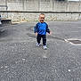 Kayden participe au concours pour gagner de l'argent avec cette photo : blue_sweatshirt, building, casual_clothing, child, cloudy_sky, curb, daylight, greenery, metal_grate, outdoor, pavement, person, sidewalk, smiling, sneakers, stone_wall, toddler, urban, walking, young_child