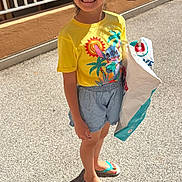 Ayna a rejoint le concours — aidez-le/la à gagner de superbes lots ! child, girl, sunglasses, yellow_tshirt, stitch_character, shopping_bag, shorts, flip_flops, smiling, outdoor, sunlight, shadow, pavement, railing, parked_cars, casual_clothing, happy, standing, summer, hair_tied