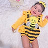 baby, infant, smiling, yellow_clothing, bumblebee_outfit, headband, flower_sign, 5_months, lying_down, white_background, cute, child, happy, portrait, soft_texture, baby_girl, closeup, adorable, one_child, indoor