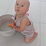 Aaron a rejoint le concours — aidez-le/la à gagner de superbes lots ! child, toddler, indoor, floor, tile, bucket, toy, plastic, curious, kneeling, clothing, shorts, sleeveless_shirt, person, skin, baby, expression, play, home, light