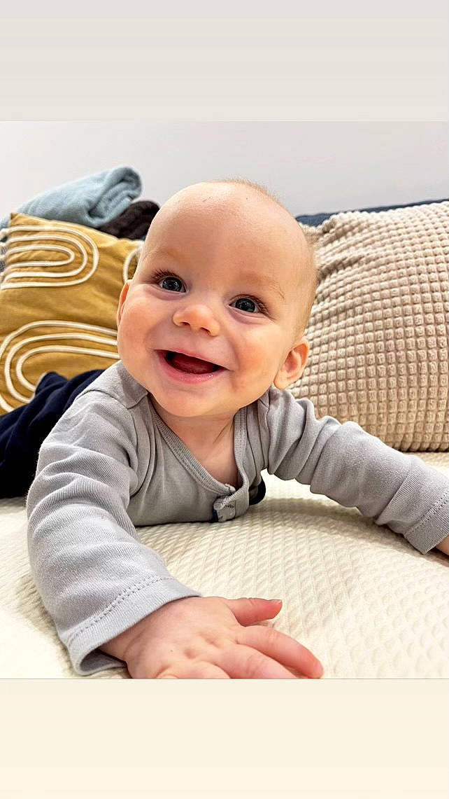 Kosta a rejoint le concours — aidez-le/la à gagner de superbes lots ! baby, baby_laughing, baby_toddler_clothing, cheek, child, comfort, face, flooring, fun, gesture, happy, joy, laugh, linens, person, portrait_photography, room, sitting, skin, sleeve