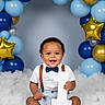 baby, boy, smiling, sitting, white_shirt, bow_tie, suspenders, number_one, balloons, blue_balloons, gold_balloons, silver_balloons, star_shaped_balloons, fluffy_surface, portrait, celebration, happy, indoor, child, cute