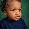 child, toddler, curly_hair, blue_sweater, portrait, studio, green_background, cute, thoughtful, face, skin, eyes, hands, clothing, fashion, young_child, person, indoors, expression, innocence