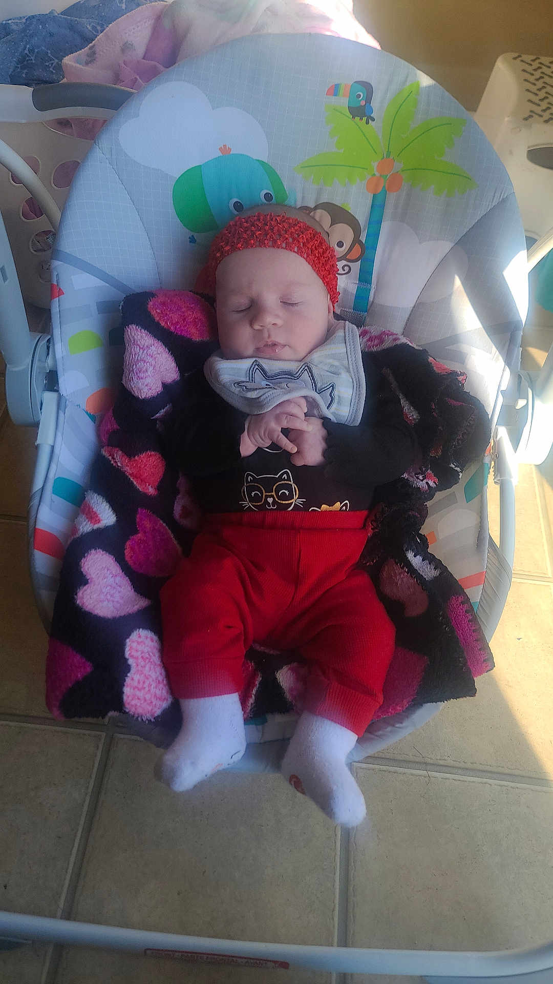 Lily joined the competition — help win amazing prizes! baby, infant, sleeping, baby_rocker, blanket, headband, red_pants, white_socks, floor_tile, indoor, baby_clothes, animal_print, palm_tree, toy_pattern, cozy, peaceful, child, resting, cute, nap