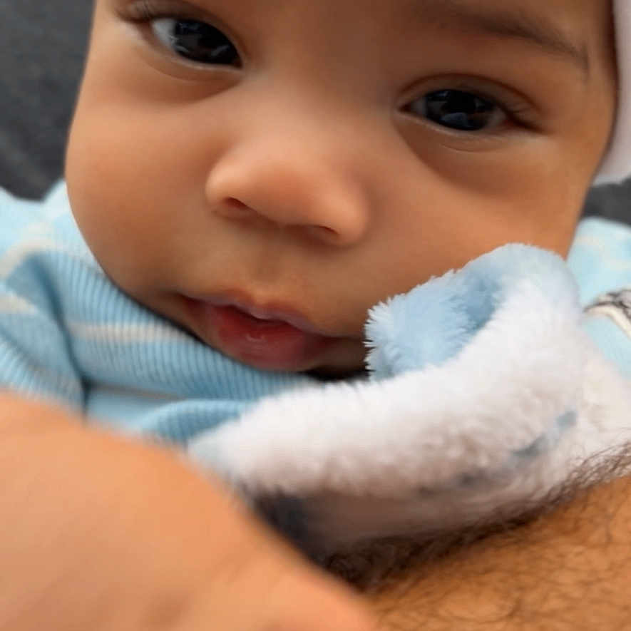 Mickayel is registered to the contest to win money with this photo: baby, blue_clothing, child, close_up, cute, eyes, face, fuzzy_blanket, hand, hat, indoor, infant, mouth, nose, person, portrait, skin, soft_texture, warm, young