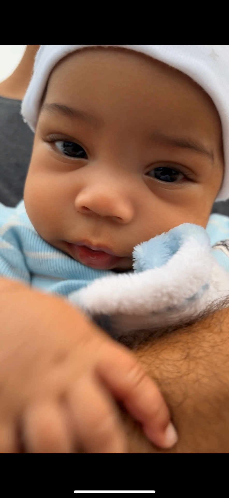 Mickayel is registered to the contest to win money with this photo: baby, close_up, infant, face, hand, hat, blue_clothing, cute, skin, eyes, nose, mouth, person, child, soft_texture, fuzzy_blanket, warm, young, portrait, indoor