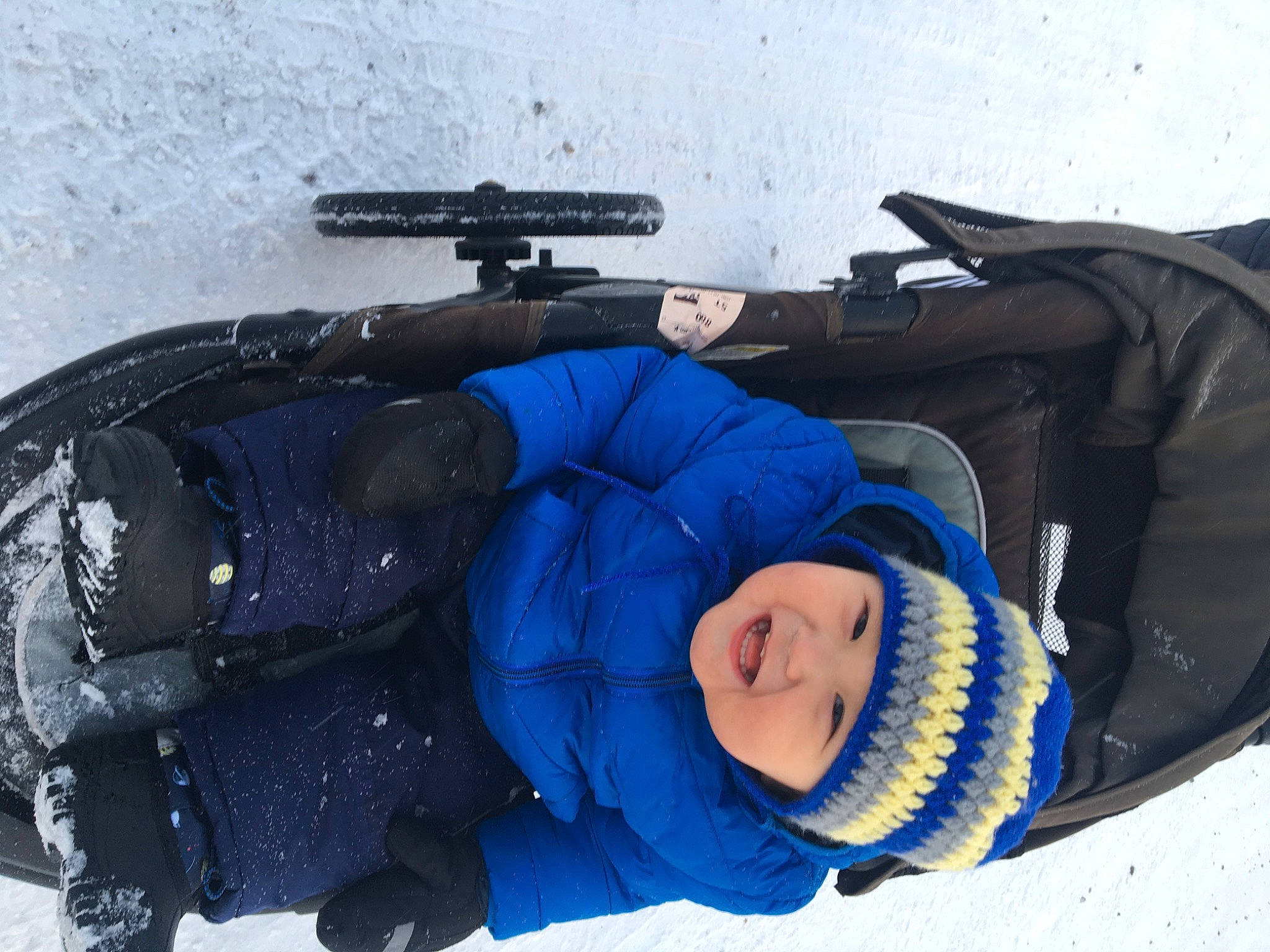 Mike is registered to the contest to win money with this photo: air_gun, automotive_tire, bag, comfort, electric_blue, freezing, glove, gun_barrel, headwear, jacket, joy, machine_gun, person, personal_protective_equipment, recreation, shooting, shotgun, smile, snow, toddler