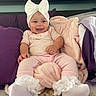 baby, infant, smile, pink_clothing, white_bow, socks, blanket, pillow, bed, indoor, face, person, cute, happy, soft_toys, headwear, child, cozy, comfort, pacifier