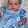 baby, child, infant, blue_dress, lace, bonnet, pillow, owl_pattern, cute, portrait, indoor, person, hand, face, expressionless, fabric, soft, newborn, clothing, lying_down