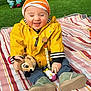 baby, infant, smiling, yellow_jacket, striped_hat, stuffed_toy, deer_toy, squeaky_toy, blanket, striped_blanket, grass, playground, boots, outdoor, seated, cute, happy, pacifier_clip, child, portrait