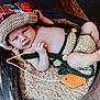 baby, infant, knitted_hat, knitted_outfit, basket, toy_fishing_rod, orange_fish_toy, wooden_floor, cozy, cute, smiling, lying_down, handmade, child, portrait, indoor, warm_colors, playful, relaxed, small_feet
