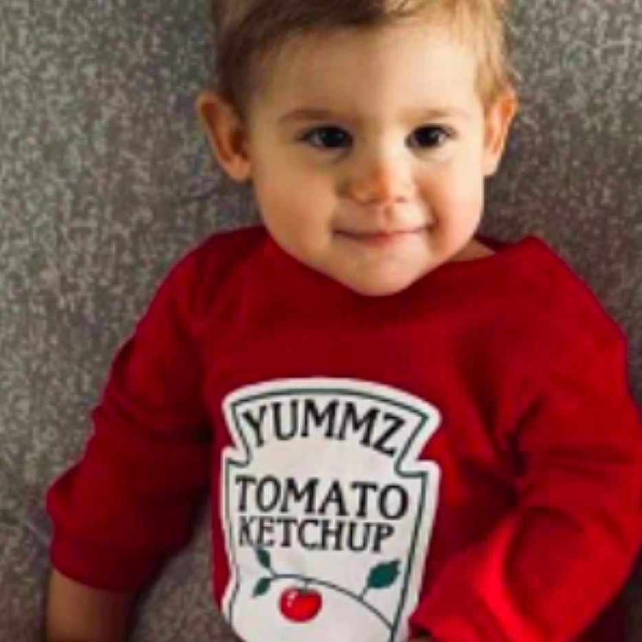 Lola participe au concours pour gagner de l'argent avec cette photo : advertisement, baby, bodypart, clothing, face, finger, food, hair, hand, happy, head, ketchup, pants, person, photography, portrait, sitting, smile, t_shirt, text