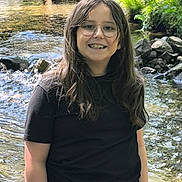 Abygail participe au concours pour gagner de l'argent avec cette photo : black_shirt, casual_clothing, child, daylight, environment, glasses, greenery, happy, long_hair, nature, outdoor, person, portrait, recreation, rocks, smiling, stream, summer, water, young
