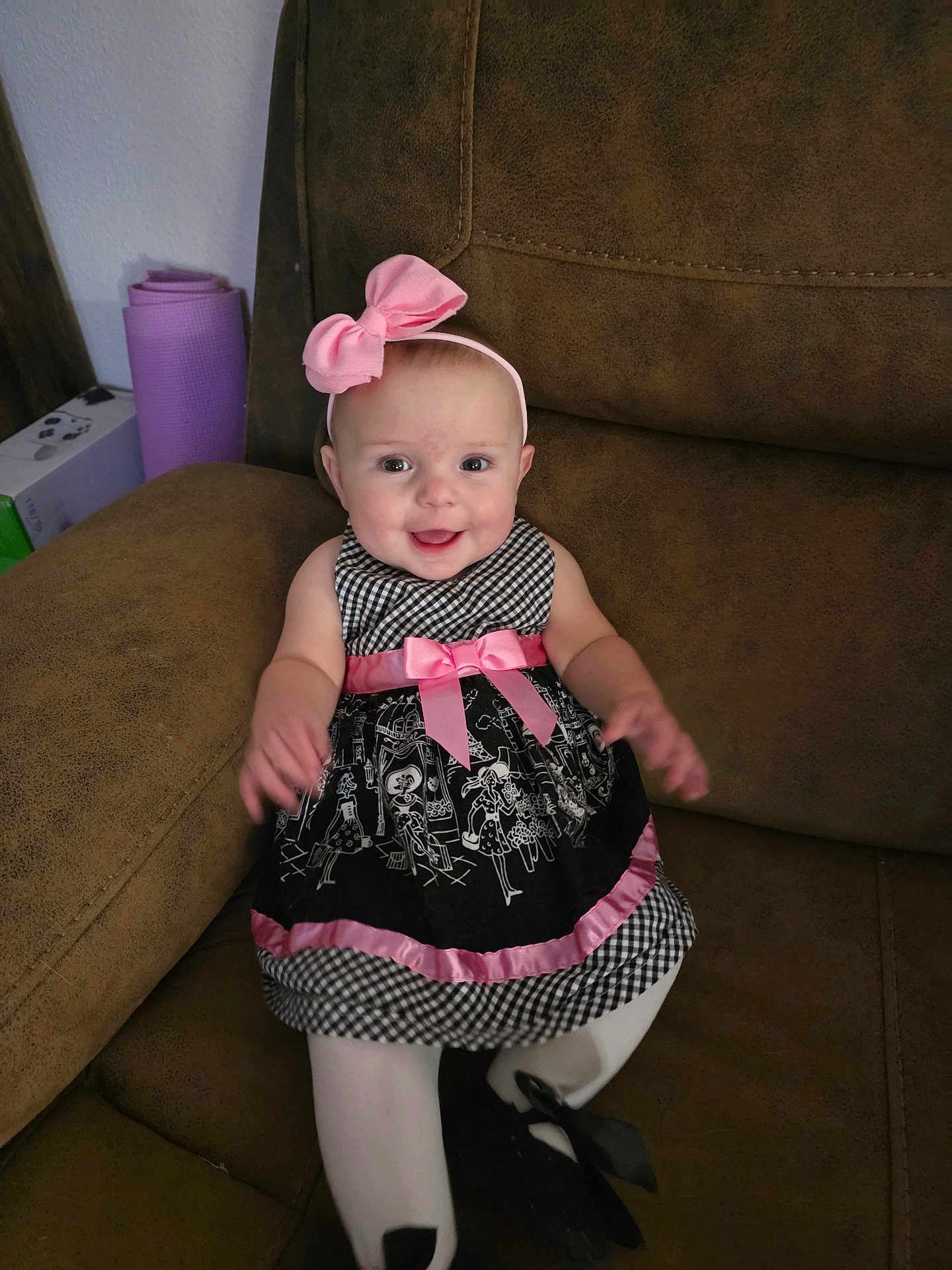 Lilley is registered to the contest to win money with this photo: baby, child, girl, smiling, headband, pink_bow, dress, black_and_white, pink_ribbon, tights, sitting, couch, furniture, indoors, happy, cute, portrait, person, young_child, head