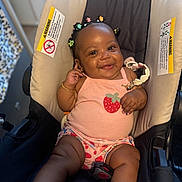 Amora is registered to the contest to win money with this photo: baby, baby_carrier, bracelet, child, comfort, cushion, cute, face, footwear, hair_clips, hand, happy, indoors, infant, pink_tank_top, portrait, seated, skin, smiling, strawberry_design