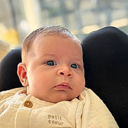 Livia a rejoint le concours — aidez-le/la à gagner de superbes lots ! baby, infant, close_up, blue_eyes, soft_skin, cream_outfit, button, embroidery, face, portrait, child, cute, indoors, blurred_background, resting, young_child, clothing, expressionless, human, newborn
