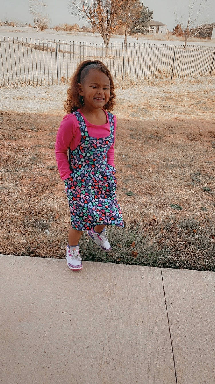 Braylee is registered to the contest to win money with this photo: baby_toddler_clothing, child, fence, fun, grass, happy, human_leg, joy, leisure, magenta, pattern, person, pink, recreation, sandal, sleeve, smile, street_fashion, summer, t_shirt