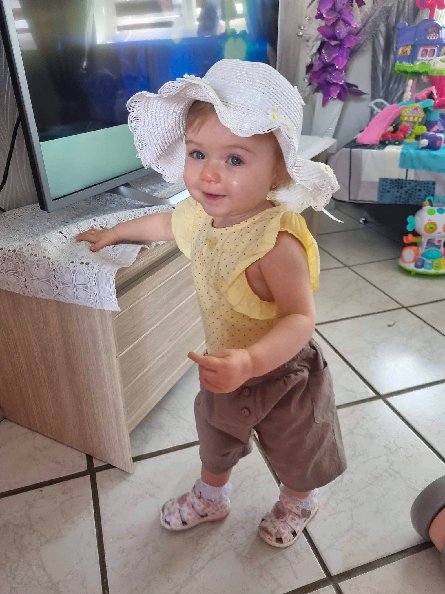 Lia a rejoint le concours — aidez-le/la à gagner de superbes lots ! baby, baby_toddler_clothing, baseball_cap, cap, child, floor, flooring, fun, happy, hat, headwear, leisure, person, pink, sandal, shoe, shorts, smile, standing, sun_hat