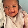 Angel is registered to the contest to win money with this photo: baby, smiling, face, bib, clothing, infant, portrait, child, cute, pink_clothing, textile, pillow, striped_fabric, closeup, happy, skin, head, eyes, mouth, indoors