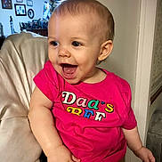Maile Sue is registered to the contest to win money with this photo: toddler, child, smiling, pink_shirt, indoor, happy, person, furniture, face, baby, sitting, armchair, home, light, casual_clothing, portrait, cute, young_child, expression, cheerful