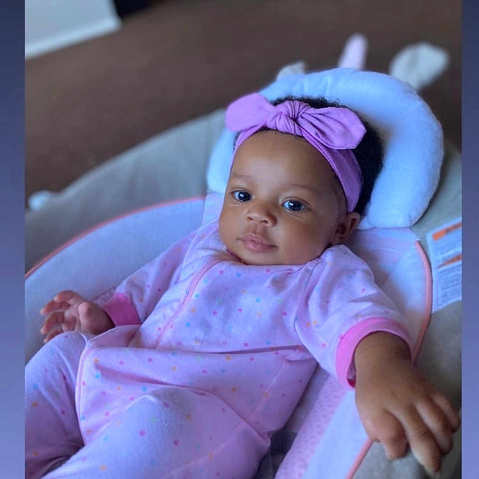 Aniyah is registered to the contest to win money with this photo: baby, bed, bodypart, bonnet, clothing, crib, face, finger, furniture, hand, happy, hat, head, infantbed, newborn, person, photography, portrait, purple, smile