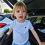 child, girl, pigtails, blue_eyes, white_tshirt, red_heart, denim_shorts, car_trunk, outdoor, daylight, curious, surprised, standing, casual_clothing, vehicle, nature_background, young_child, portrait, expression, hands