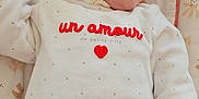 éloïse participe au concours pour gagner de l'argent avec cette photo : baby, infant, child, sleepwear, white_clothing, red_text, soft_toys, patterned_cushion, lying_down, portrait, peaceful, cute, small_hand, face, head, indoors, cozy, warm_colors, closeup, newborn