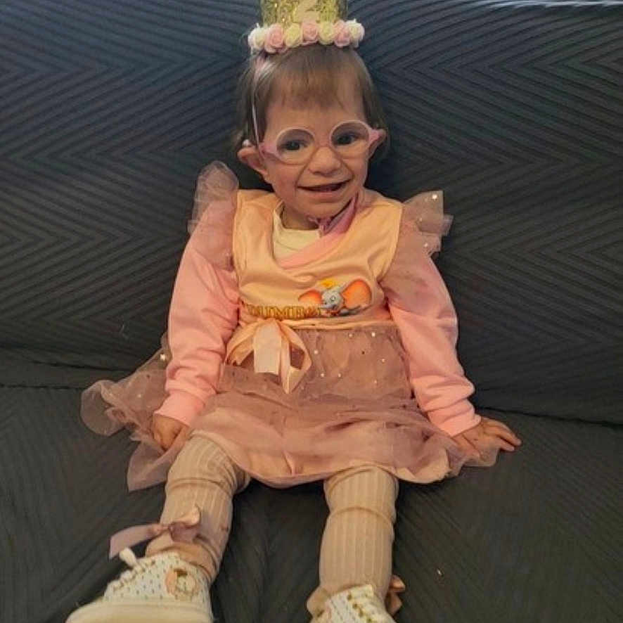 Elyana Desmettre participe au concours pour gagner de l'argent avec cette photo : birthday, celebration, child, couch, crown, curtain, cute, glasses, happy, home, indoor, party, pink_dress, sitting, smiling, sneakers, striped_tights, toddler, tutu, young_child