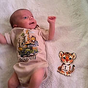 Asaiah joined the competition — help win amazing prizes! baby, infant, one_month, blanket, clothing, onesie, animal_print, tiger_illustration, cute, milestone, soft_texture, lying_down, child, portrait, smiling, indoor, young_child, baby_garment, animal_design, happy