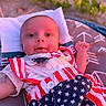 Asaiah is registered to the contest to win money with this photo: baby, blanket, blue, child, clothing, cute, eyes, face, infant, lying_down, nature, outdoor, pattern, pillow, red, smile, soft_light, stars, stripes, white