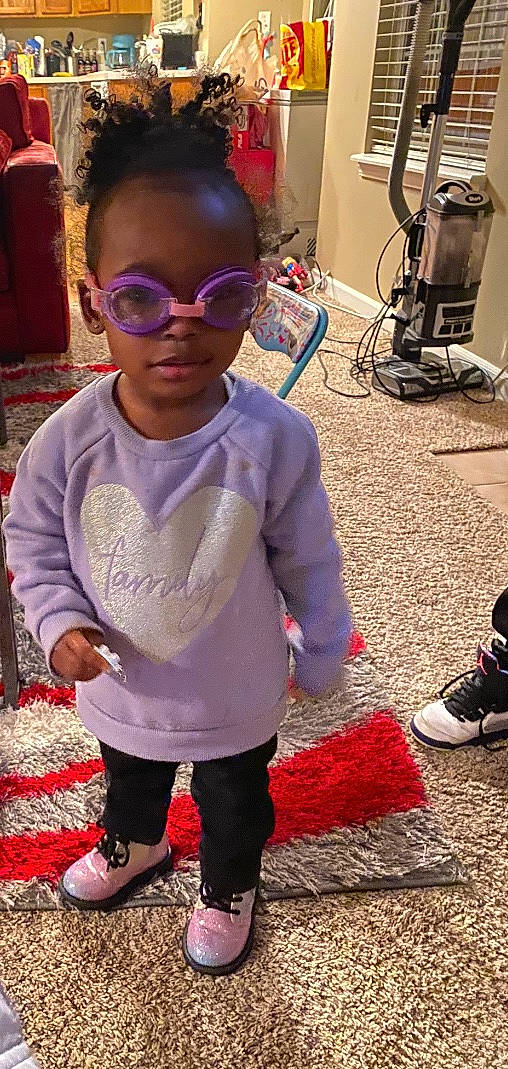 Stori is registered to the contest to win money with this photo: baby_toddler_clothing, child, cool, eyewear, face, facial_expression, flooring, fun, goggles, human, magenta, person, pink, purple, red, shoe, sleeve, sunglasses, toddler, vision_care