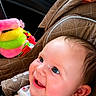 baby, child, car_seat, smiling, blue_eyes, plush_toy, colorful_toy, quilted_fabric, seatbelt, car_interior, window, greenery, happy, infant, portrait, cute, young_child, side_view, bright, indoors