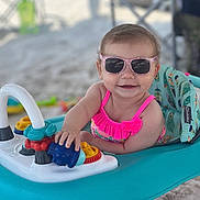 Kadi joined the competition — help win amazing prizes! baby, baby_walker, beach, child, colorful, cute, fun, happy, outdoor, person, pink_swimsuit, play, sand, seat, smiling, summer, sunglasses, sunny, toys, vacation