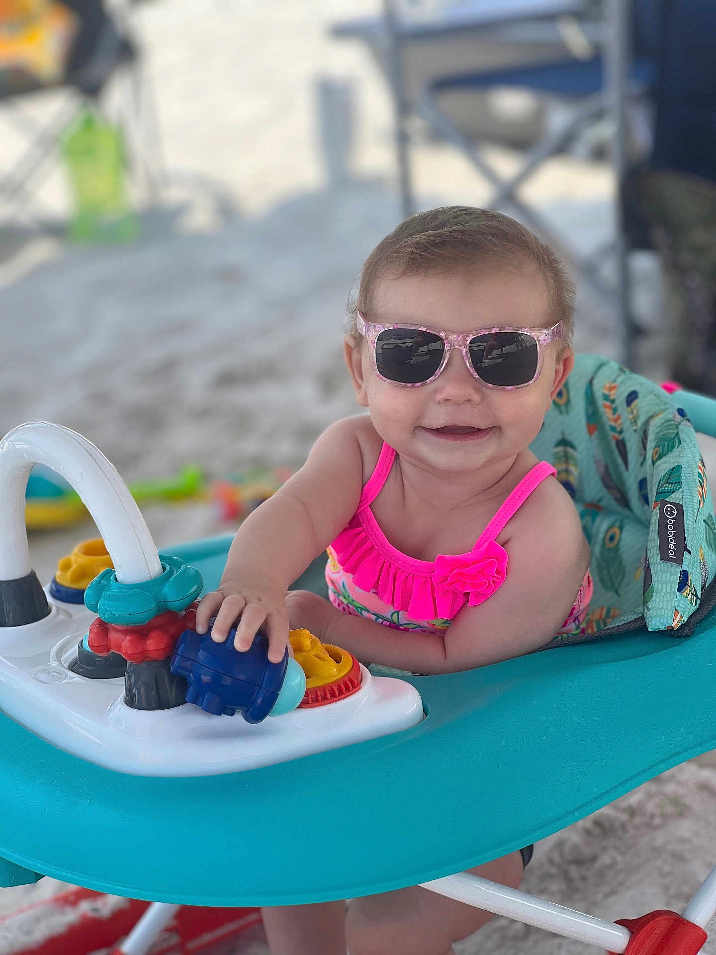 Kadi joined the competition — help win amazing prizes! baby, baby_walker, beach, child, colorful, cute, fun, happy, outdoor, person, pink_swimsuit, play, sand, seat, smiling, summer, sunglasses, sunny, toys, vacation
