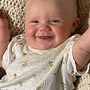 Zoey joined the competition — help win amazing prizes! baby, smile, face, infant, child, clothing, white_shirt, lemon_print, knitted_blanket, happy, cheeks, arms_raised, cute, portrait, closeup, indoor, person, head, skin, joyful