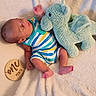 baby, infant, onesie, striped_clothing, stuffed_animal, plush_toy, blue_toy, blanket, soft_texture, wooden_sign, age_marker, newborn, cute, lying_down, indoors, child, person, feet, head, milestone