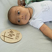 Asher joined the competition — help win amazing prizes! baby, infant, lying_down, two_months, milestone, wooden_plaque, cute_outfit, animal_prints, soft_surface, portrait, child, young, skin, face, hand, eyes, casual_clothing, indoor, newborn, calm