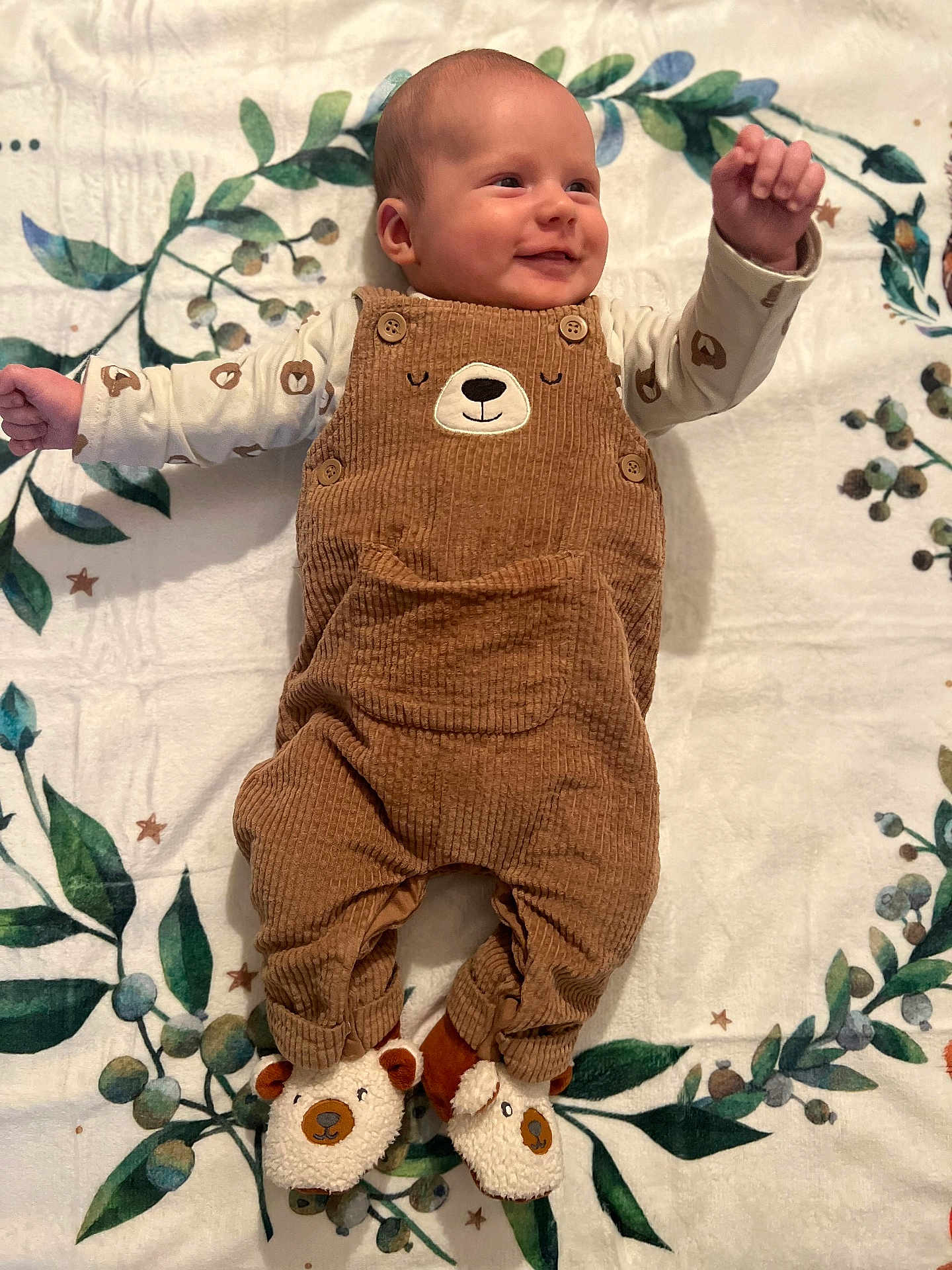 Léo participe au concours pour gagner de l'argent avec cette photo : adorable, baby, bear_design, blanket, brown_overalls, buttoned_overalls, child, cute, footwear, happy, indoor, infant, leaf_pattern, long_sleeve_shirt, lying_down, portrait, slippers, small_hands, smiling, soft_texture