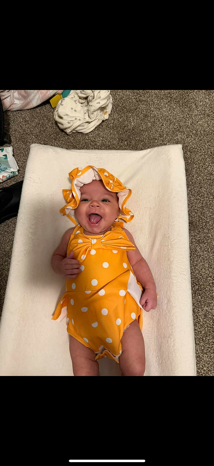 Aila joined the competition — help win amazing prizes! baby, infant, smiling, yellow_clothing, polka_dot, bonnet, lying_down, happy, carpet, white_blanket, cheerful, child, cute, indoors, one_person, small_baby, apparel, headwear, skin, playful