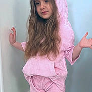 Emma joined the competition — help win amazing prizes! child, pink_clothing, unicorn_hood, hoodie, shorts, long_hair, indoor, pose, playful, casual, footwear, light_blue_wall, white_door, flooring, young_girl, cute, relaxed, portrait, fashion, costume